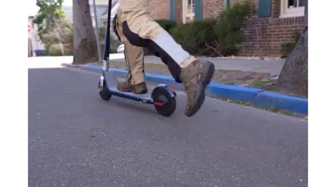 A man kicking off an electric scooter to start it