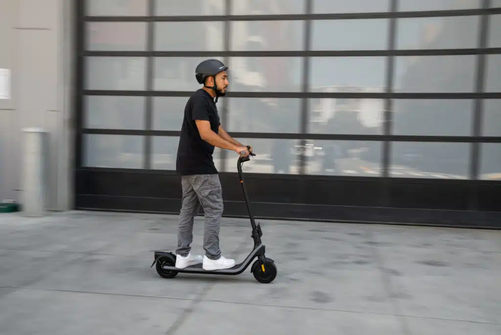 man riding segway ninebot e2 electric scooter in front of reflective glass