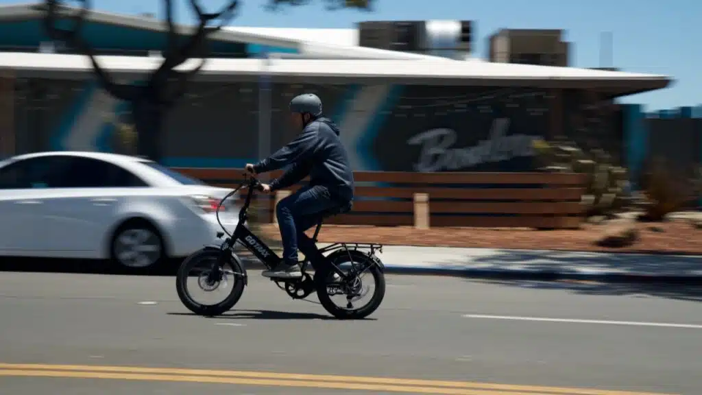 mitchell riding the gotrax f2 e-bike past a restaurant