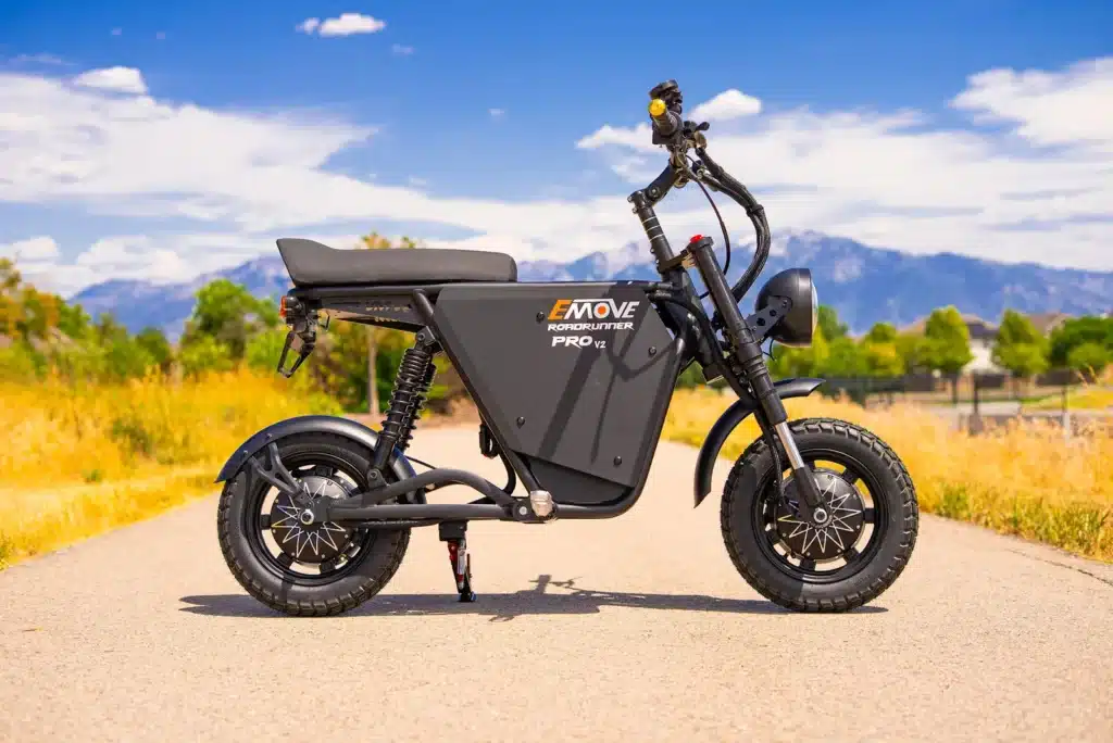 EMOVE RoadRunner Pro V2 electric moto minibike parked on a path with snow-capped mountains behind