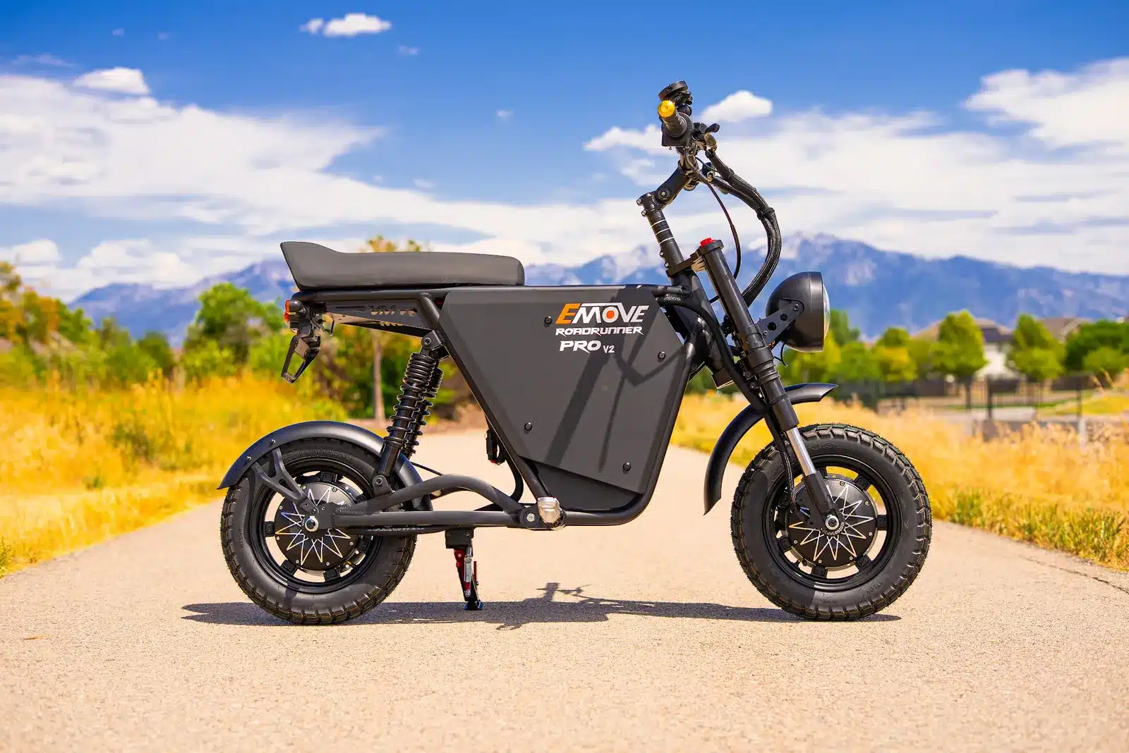 EMOVE RoadRunner Pro V2 Review: Surron Power in a Tiny, Stealthy Package 1 EMOVE RoadRunner Pro V2 electric moto minibike parked on a path with snow-capped mountains behind